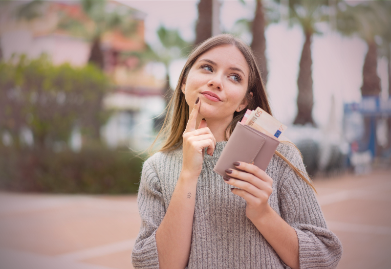 Mulher segurando carteira com dinheiro, simbolizando autoconhecimento financeiro.