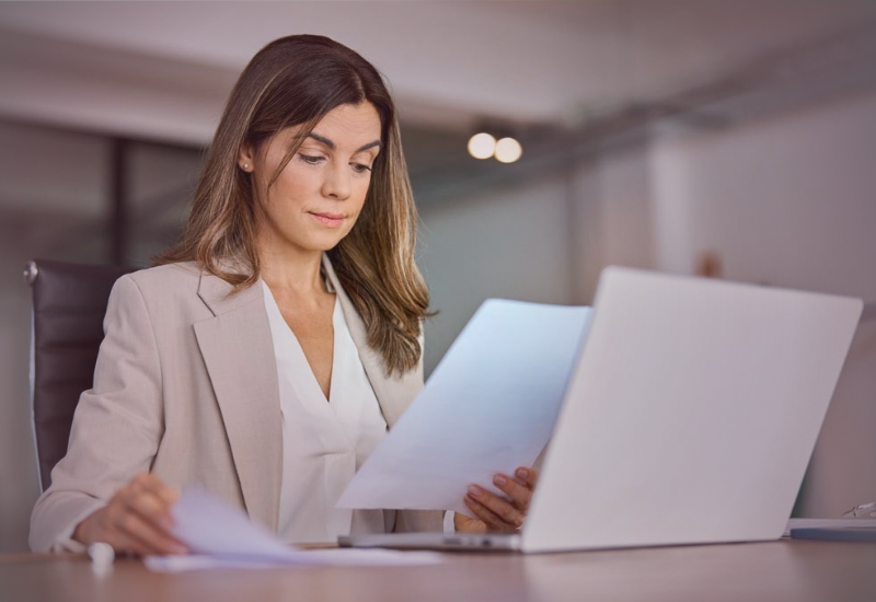 Mulher analisando documentos antes de contratar um profissional, avaliando critérios, prazos e responsabilidades no ambiente corporativo