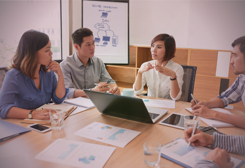 Líder orientando equipe durante reunião, estimulando autonomia e desenvolvimento profissional.