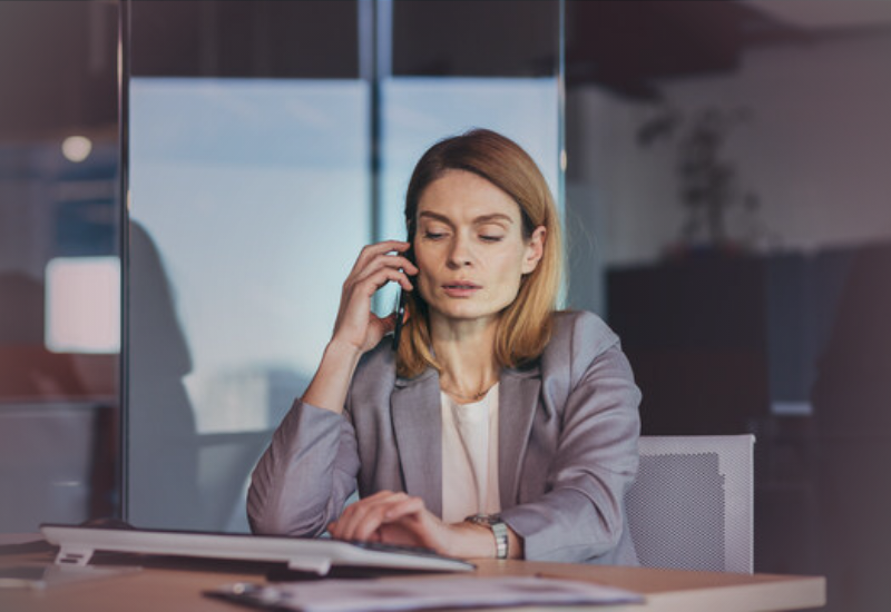Líder em escritório recebendo uma ligação enquanto trabalha, representando o impacto das crises familiares no ambiente empresarial.