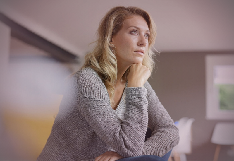 Mulher madura sentada em ambiente tranquilo, com expressão serena e postura firme, representando decisão consciente, limites emocionais e maturidade após uma escolha difícil.