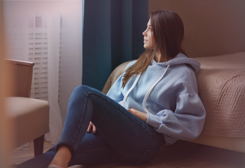 Mulher sentada no chão, em momento de reflexão silenciosa, representando relações onde apenas os sentimentos do outro importam e o impacto emocional do autoabandono.